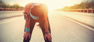 Tired Woman Runner Bent Over With Hands On Knees Taking A Rest After Running Hard