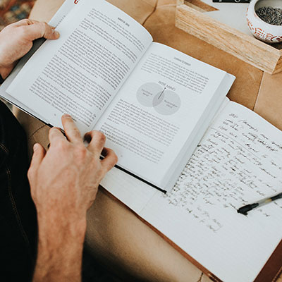 A picture of the book GROUNDED-leading your life with intention open with the hands of a reader and his notes next to the book.