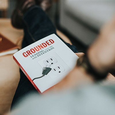 A photograph of the book GROUNDED-leading your life with intention taken over the shoulder of a reader.