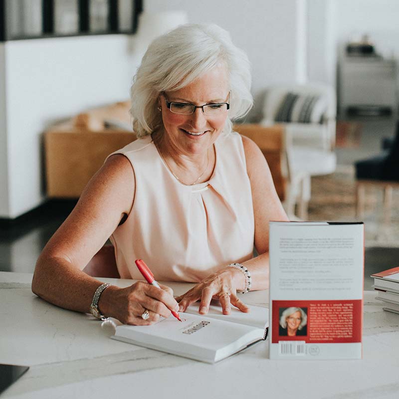 A photograph of Nancy M. Dahl signing her book GROUNDED, leading your life with intention