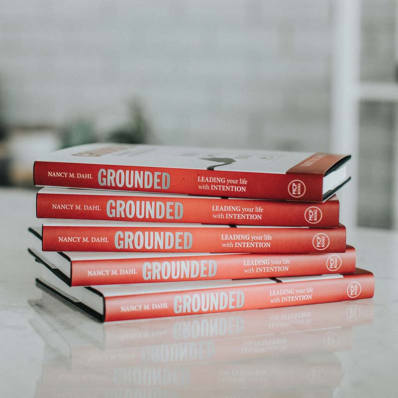 A photograph of a stack of the book GROUNDED, leading your life with intention.