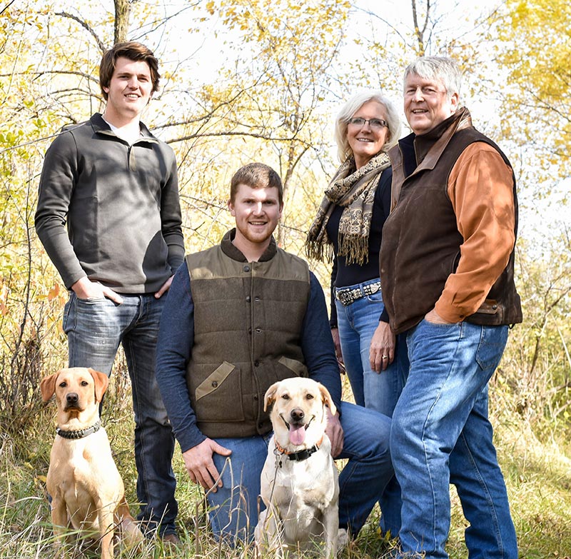 An outdoor casual photograph of Nancy M. Dahl with her family including Brian Dahl, Jorgen Dahl, Erik Dahl and their dogs Ellie and Thea.