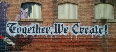 A Photograph Of Graffiti On A Brick Wall That Reads, Together We Create